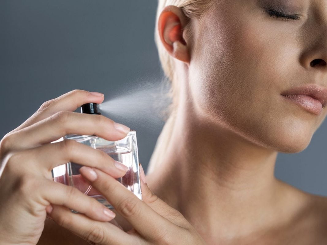 Žena nanosi parfem na vrat